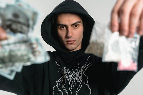 Close-up of a person holding drugs and money, illustrating the cycle of addiction and its impact.