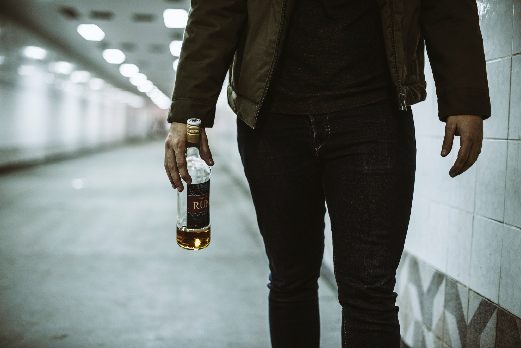 Close-up of a person gripping a liquor bottle, representing the emotional burden of alcohol addiction.