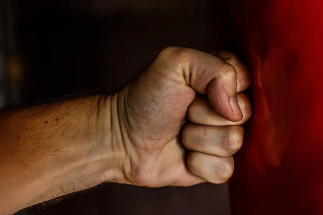 Person in a moment of rage, punching a wall as a release of uncontrolled anger.
